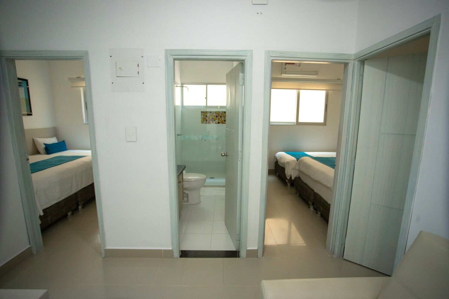 A hotel room with a bathroom, a shower, and a small sitting area.