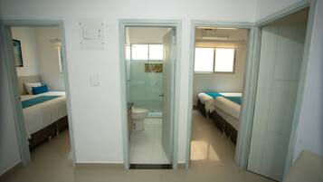 A hotel room with a bathroom, a shower, and a small sitting area.