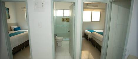 A hotel room with a bathroom, a shower, and a small sitting area.
