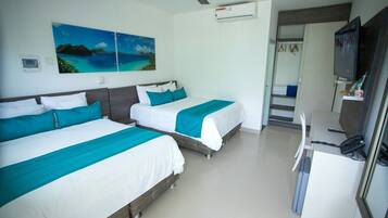A hotel room with two beds, a desk, a chair, a TV, and a ceiling fan.