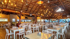 A spacious restaurant with numerous tables and chairs, a high ceiling with exposed beams, and hanging lights. - Hotel Poblado Coveñas (Coveñas)