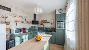 A kitchen with teal cabinets, a wooden countertop, and a fruit bowl. - Ellisa - Jolie Maison proche de la mer (Ver-sur-Mer)