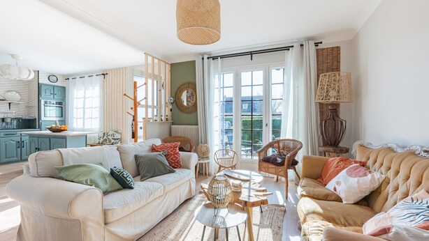 A spacious living room with a sofa, armchairs, a coffee table, and a dining table. There is a kitchen area visible in the background. - Ellisa - Jolie Maison proche de la mer (Ver-sur-Mer)