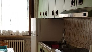 Una cocina con gabinetes verdes, un refrigerador blanco, un fregadero y una estufa.