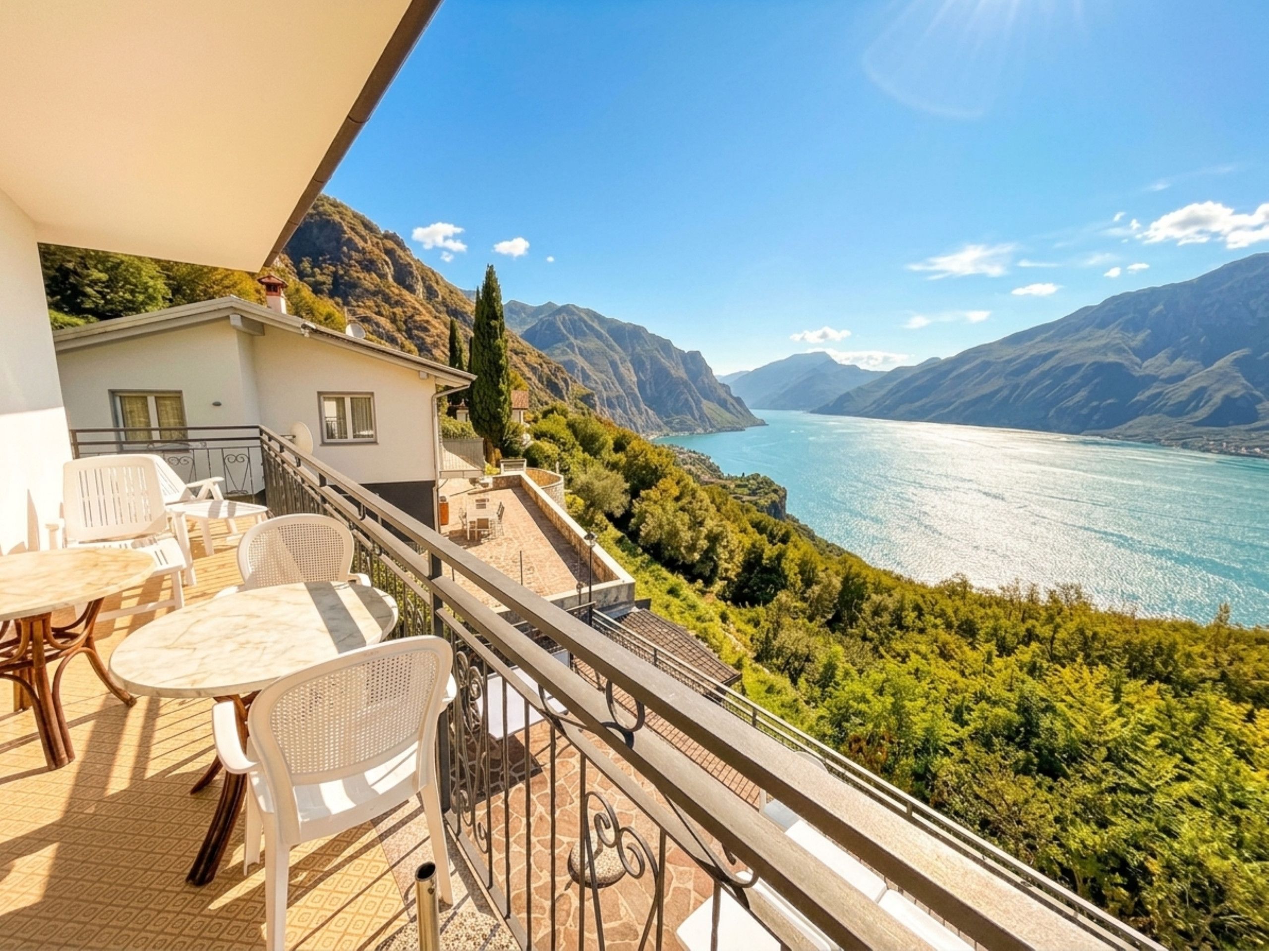 Ein Balkon mit Gartenmöbeln und Blick auf einen See und Berge.
