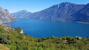 Un paysage montagneux avec un grand lac, un petit village composé de quelques bâtiments et une végétation luxuriante.
