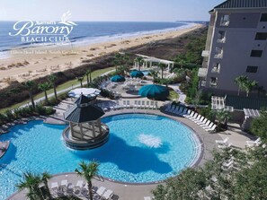 Relax by the pool surrounded by lounge chairs and umbrellas, with a scenic view of the adjacent beach.