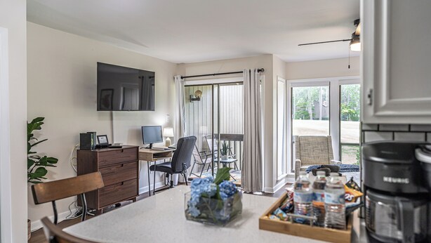 A modern kitchen with a dining area, a flat-screen TV, and a coffee maker.