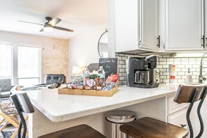 A modern kitchen with a coffee maker, a chalkboard sign, and snacks on the counter.