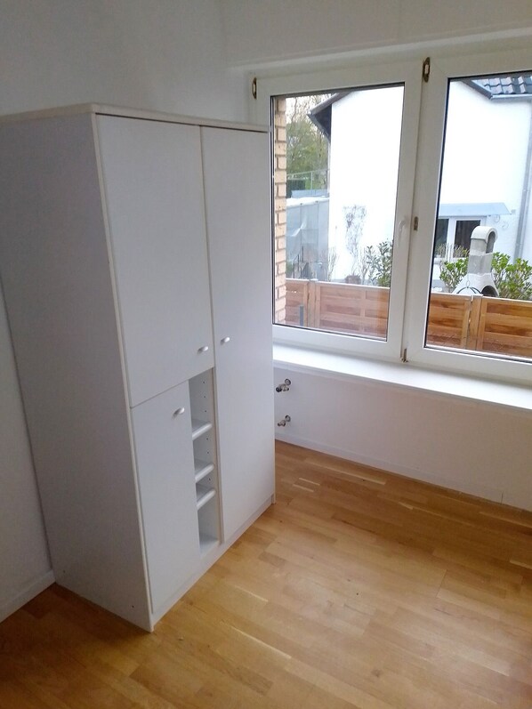 A room with a large window, wooden flooring, and a white wardrobe. - Quiet and central incl. parking lot (Bad Honnef)