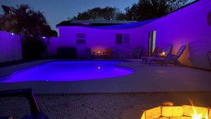 Ein Garten mit Swimmingpool, Feuerstelle und Gartenmöbeln.