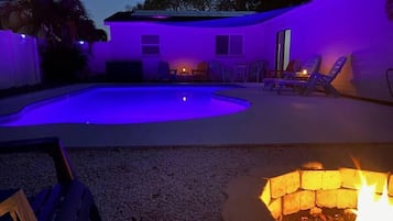 Ein Garten mit Swimmingpool, Feuerstelle und Gartenmöbeln.