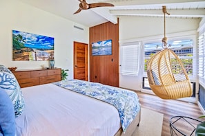 Un dormitorio con cama, armario de madera y una silla colgante.