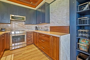 Eine moderne Küche mit dunklen Schränken, einer Holzarbeitsplatte, einem eingebauten Backofen und einer Marmor-Spritzschutzwand.