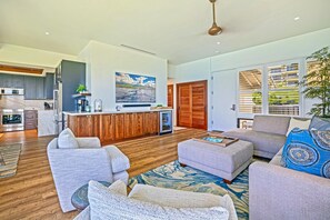 Ein modernes Wohnzimmer mit einem grauen Sofa, einem Couchtisch und einem gemusterten Teppich.