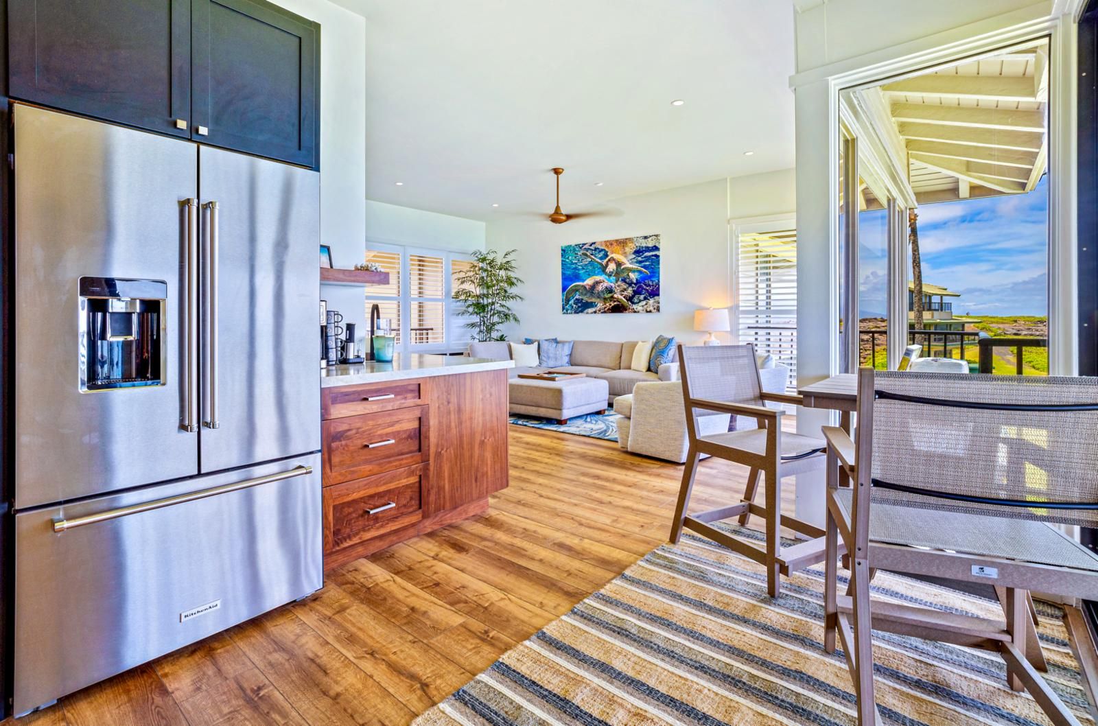 A modern kitchen with a stainless steel refrigerator, wooden cabinets, and a dining area with a table and chairs.