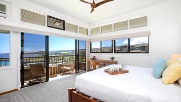 A bedroom with a large bed, a ceiling fan, and a balcony with a view.