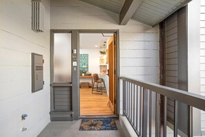 A hallway leading to a dining area with a wooden floor and a metal railing. - Kapalua Ridge | Ocean View 1 BR | Cozy Villa | Car Incl. w/ 6+ Nights | KRV-2823 by KBM (Lahaina)