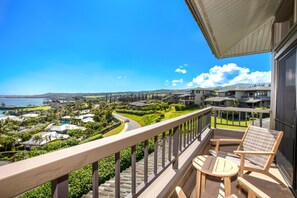 A balcony with a view of a coastal landscape, including houses and a road. - Kapalua Ridge | Ocean View 1 BR | Cozy Villa | Car Incl. w/ 6+ Nights | KRV-2823 by KBM (Lahaina)