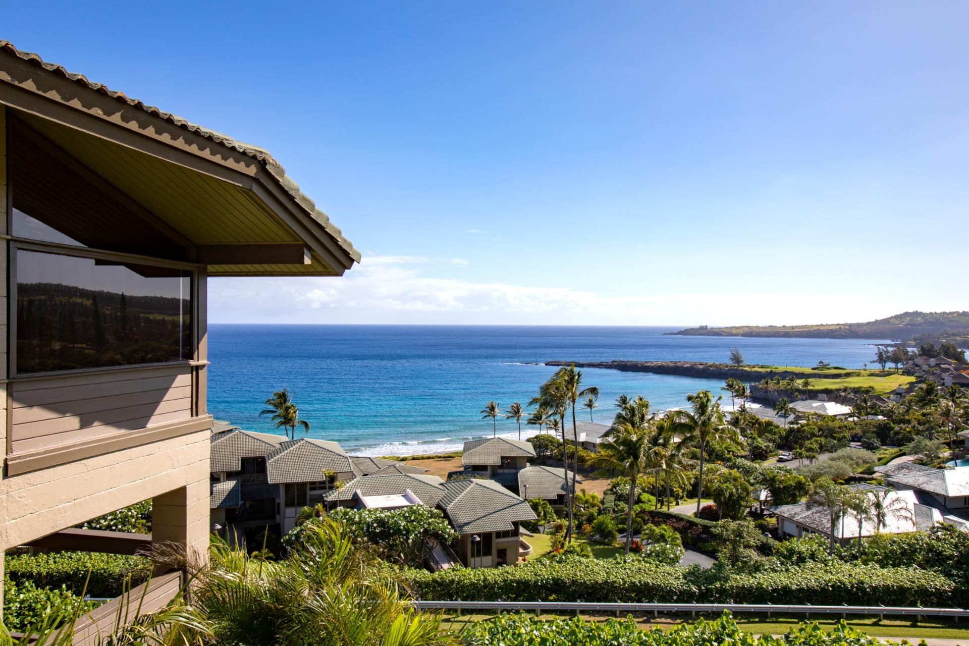 A coastal property with a view of the ocean, multiple buildings with similar architecture, and lush greenery.