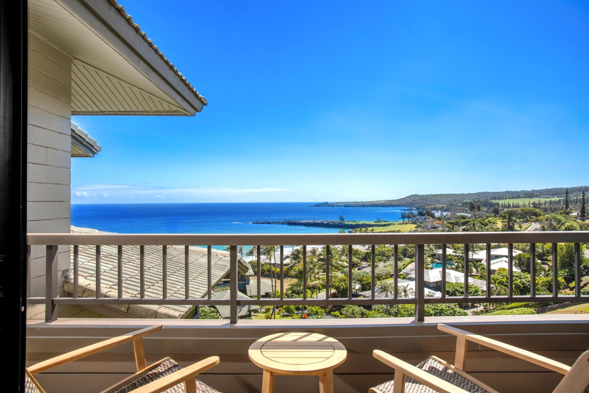 A balcony with a view of the ocean and a residential area.