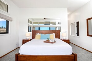 Ein Hotelzimmer mit einem großen Bett, zwei Nachttischen, Blick auf den Himmel und einem Balkon.