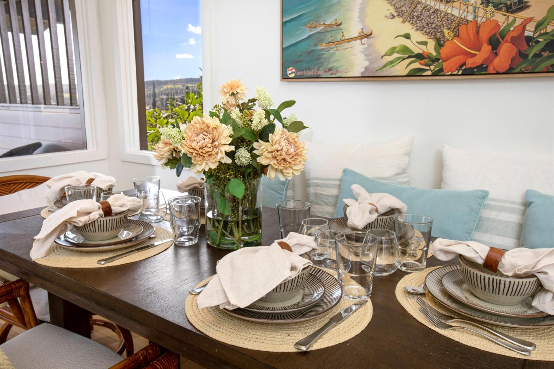 A dining table set with plates, glasses, and a vase of flowers.