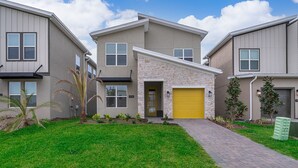 A modern two-story house with a stone facade, a yellow garage door, and a well-maintained lawn.