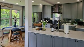 Une cuisine moderne avec des meubles gris, des appareils en acier inoxydable et une grande fenêtre.