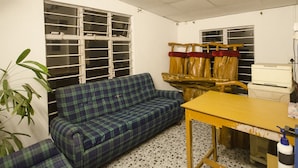 A room with a plaid sofa, a wooden table, and a window with blinds. - Quiet yet located in the heart of the city....! (Guwahati)