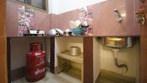A compact kitchen with a gas cylinder, a sink, and a window above the counter. - Quiet yet located in the heart of the city....! (Guwahati)