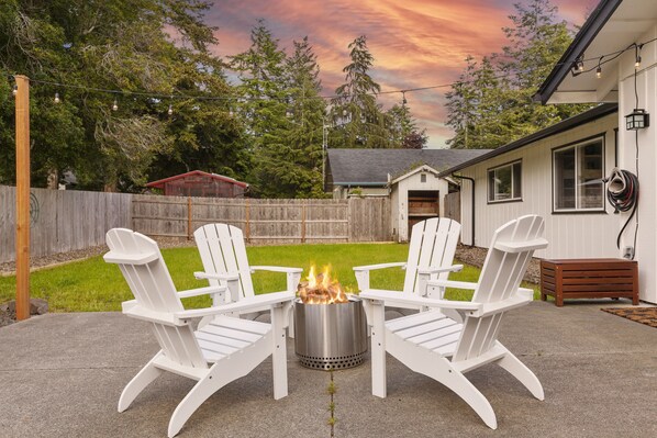 A patio with four white Adirondack chairs arranged around a metal fire pit. - Year Round Fun - Dog Friendly! (Florence)