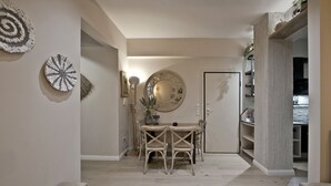 A dining area with a round table and chairs, a wall-mounted mirror, and a shelf with books and decorative items. - Stylish Apartment at Pagrati (Vironas)