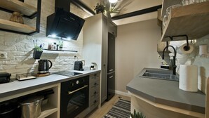 A modern kitchen with a brick wall, a built-in oven, a coffee machine, and a hanging light fixture. - Stylish Apartment at Pagrati (Vironas)