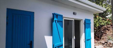 A building with a white exterior, a blue door, and a blue window shutter.