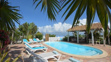 Una piscina al aire libre, sillones reclinables de piscina