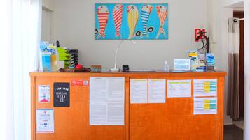 A reception desk with a ceiling fan, a painting of fish, and various informational notices.