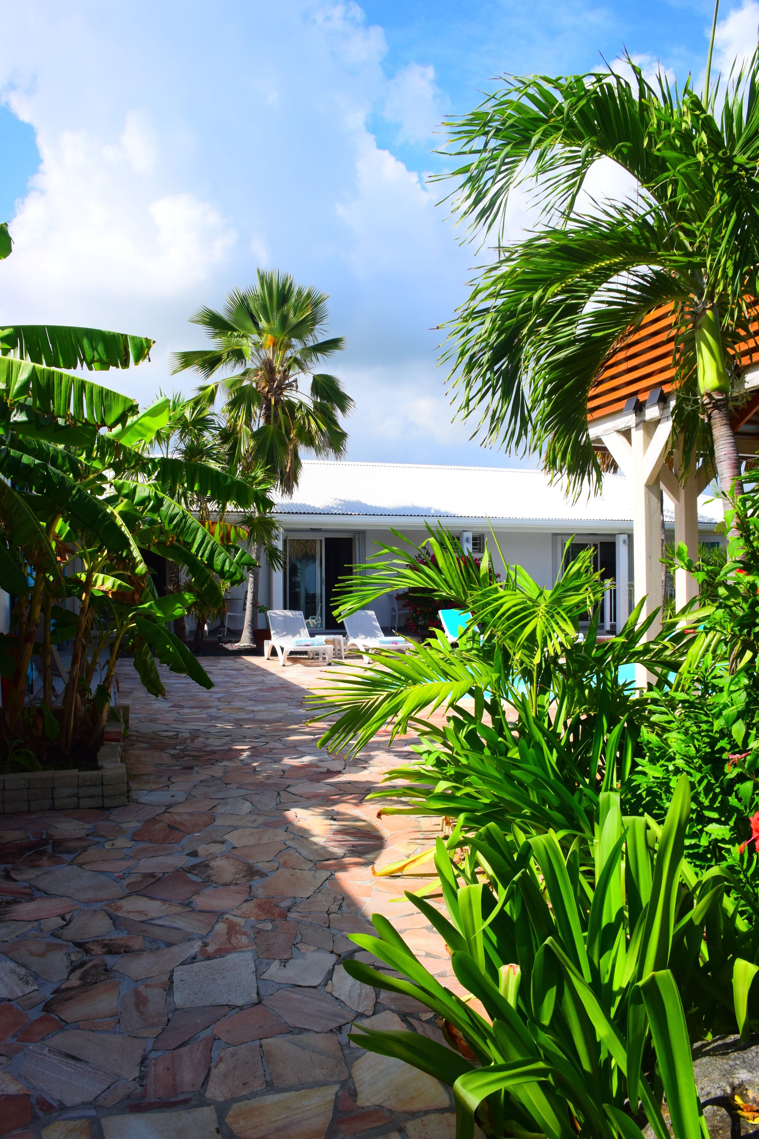 A stone pathway leading to a white building with a covered patio area.