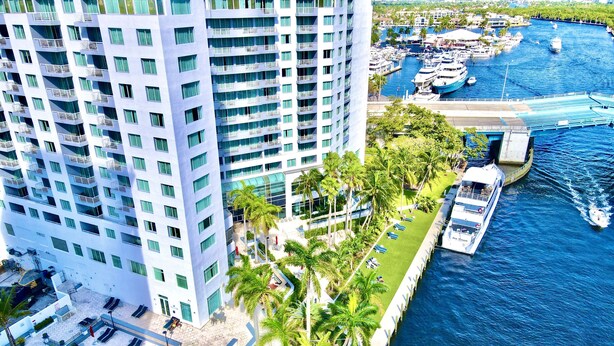 A high-rise hotel with a pool, palm trees, and a marina with boats. - Apart Suites By Hilton. Top View. (Fort Lauderdale)