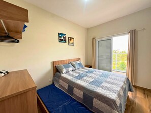 A bedroom with a bed, a desk, a wardrobe, and a window with a view.