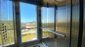 Ein Aufzug mit großem Fenster, Metallhandlauf und Bedienfeld.