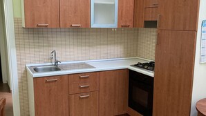 A compact kitchen with wooden cabinets, a stainless steel sink, and a built-in oven.