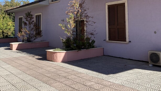 A two-story building with a tiled patio and a small garden area.