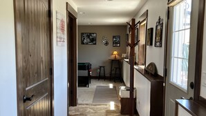 Un couloir avec des portes en bois, un sol carrelé et une lampe à l’arrière-plan.