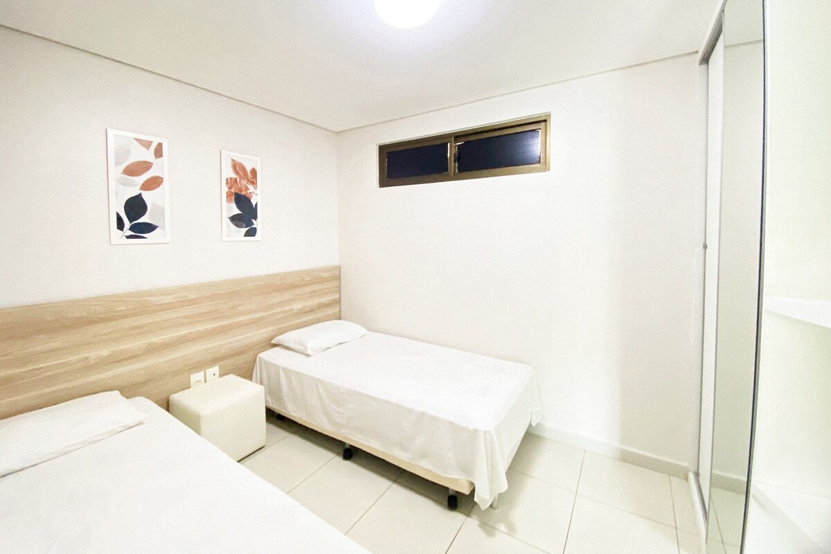 Una habitación con dos camas, una mesita y una ventana.