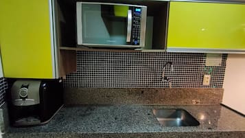 A kitchen with a microwave, coffee maker, and tiled backsplash.