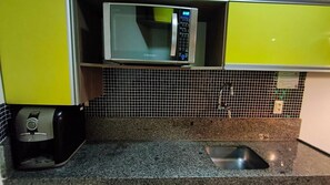 Eine Küche mit Mikrowelle, Kaffeemaschine und gefliestem Spritzschutz.
