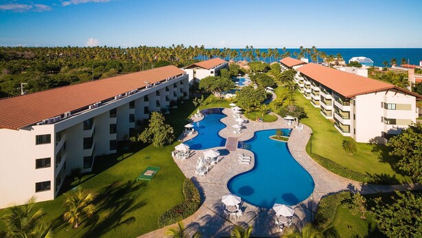 A resort with a swimming pool, multiple buildings, and a view of the ocean. - Carneiros Beach Resort - Praia Carneiros (Tamandaré)