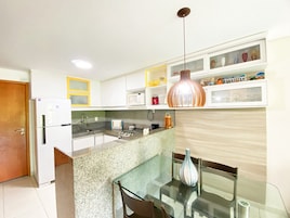 Una cocina moderna con una isla integrada, microondas y una lámpara colgante.