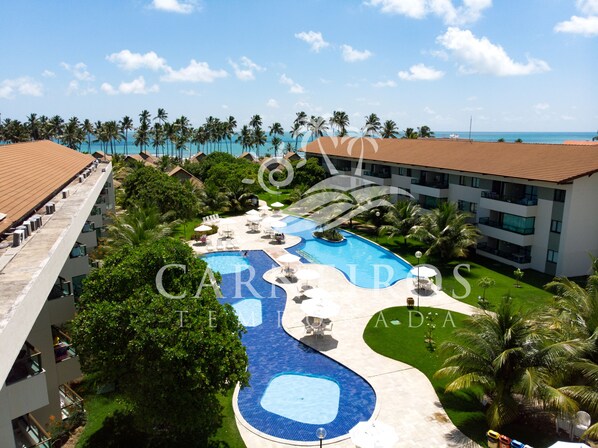 Relax by the infinity pool overlooking the ocean, surrounded by lush greenery and palm trees.